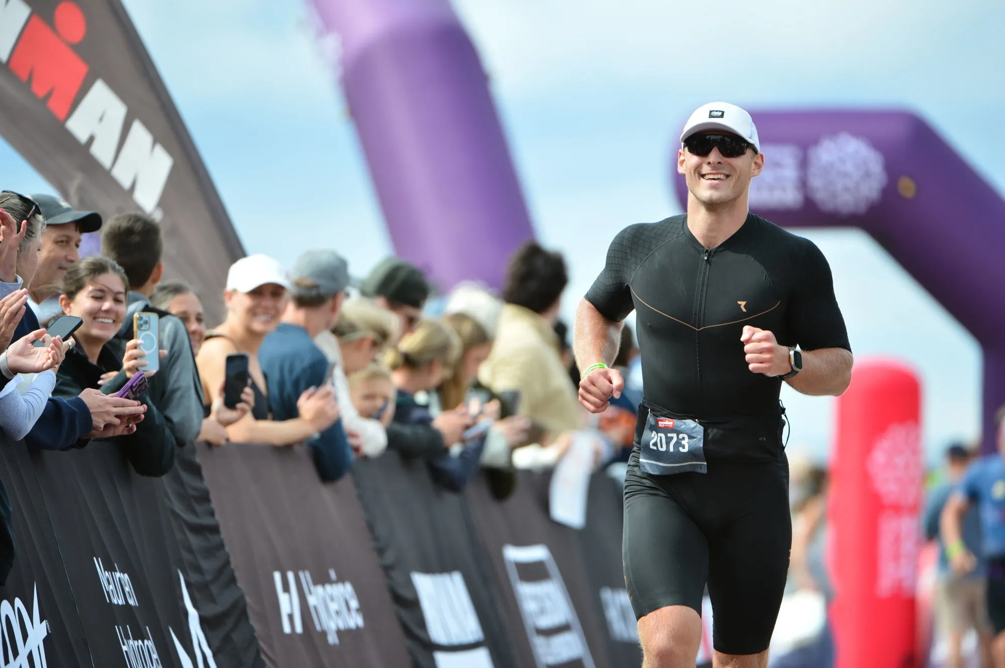 James smiling as he runs down the finish chute at Ironman 70.3 Michigan, bib 2073